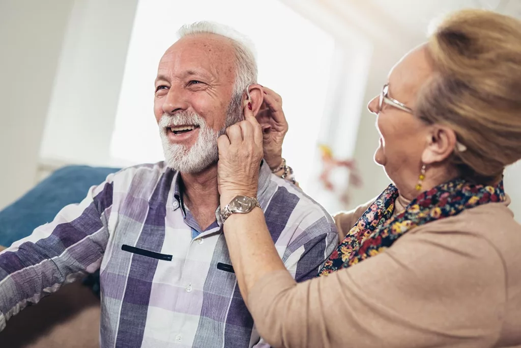 Man having his hearing aid checked for cleanliness by a hearing aid specialist